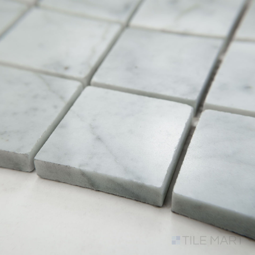 Angled view of White Carrara Marble 2" square polished mosaic featuring shiny marble squares that enhance a classic and luxurious look