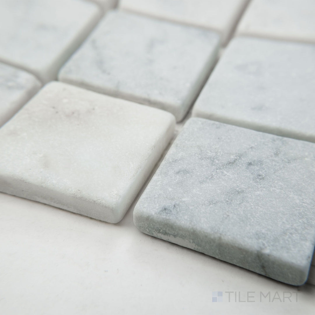 Tile shown from corner angle of White Carrara Marble 2" square tumbled mosaic revealing a weathered marble texture with natural charm