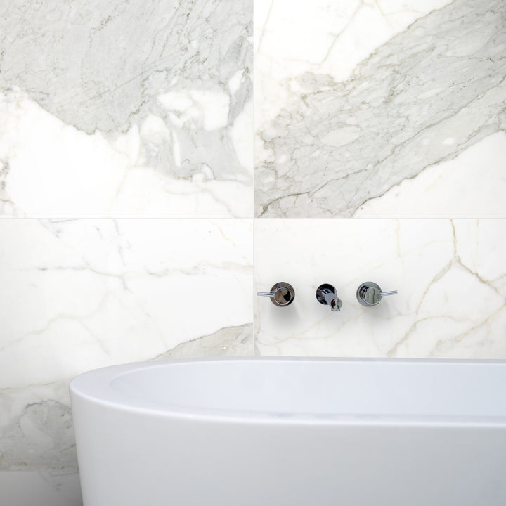 Lifestyle image of Calacatta Gold Marble 24x24 Honed Tile installed on the floor, showcasing luxurious white marble with bold gold veining in an upscale interior setting.