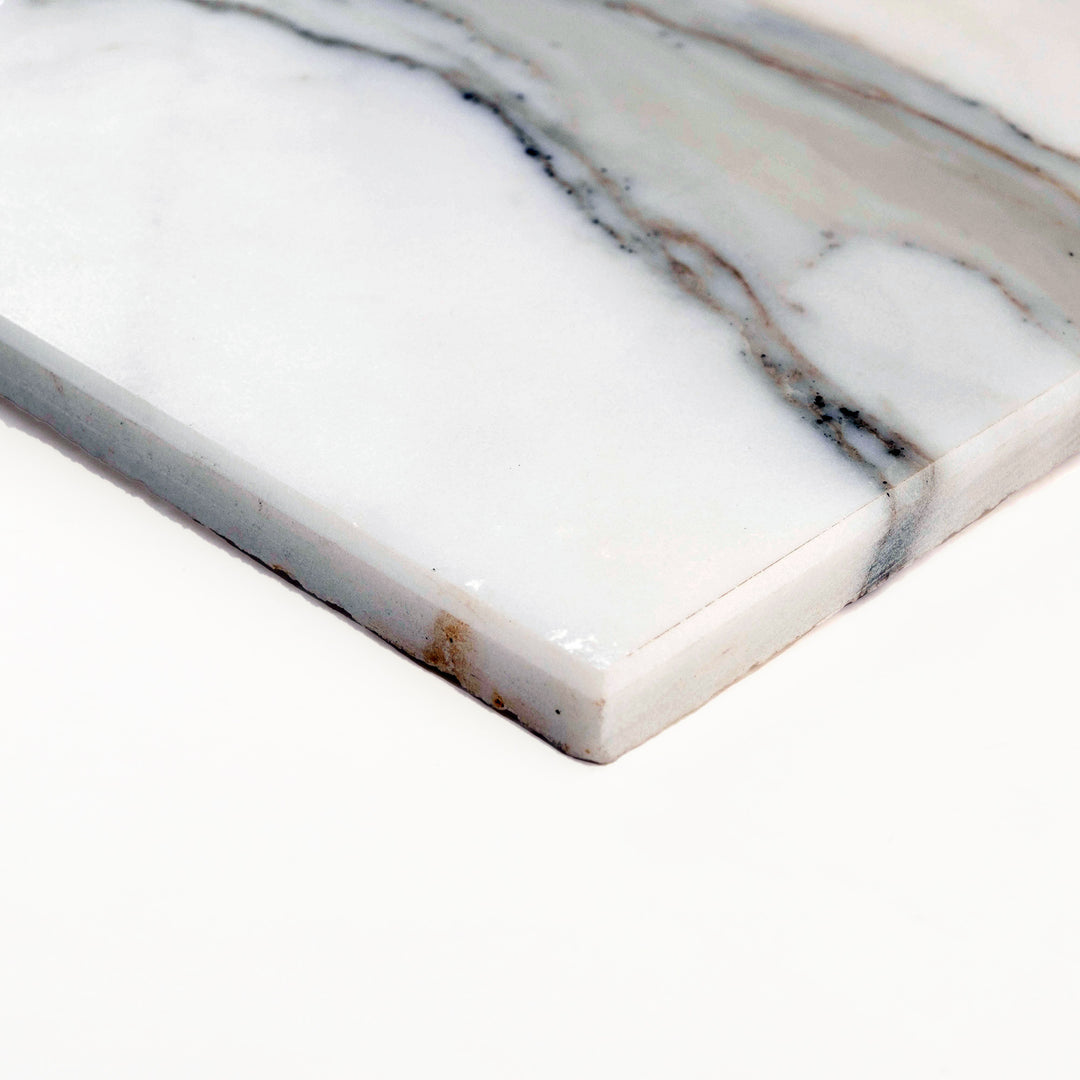 Honed Calacatta Gold Marble 24x24 tile photographed at an angle, showcasing a grand square format with soft matte finish and subtle veining.