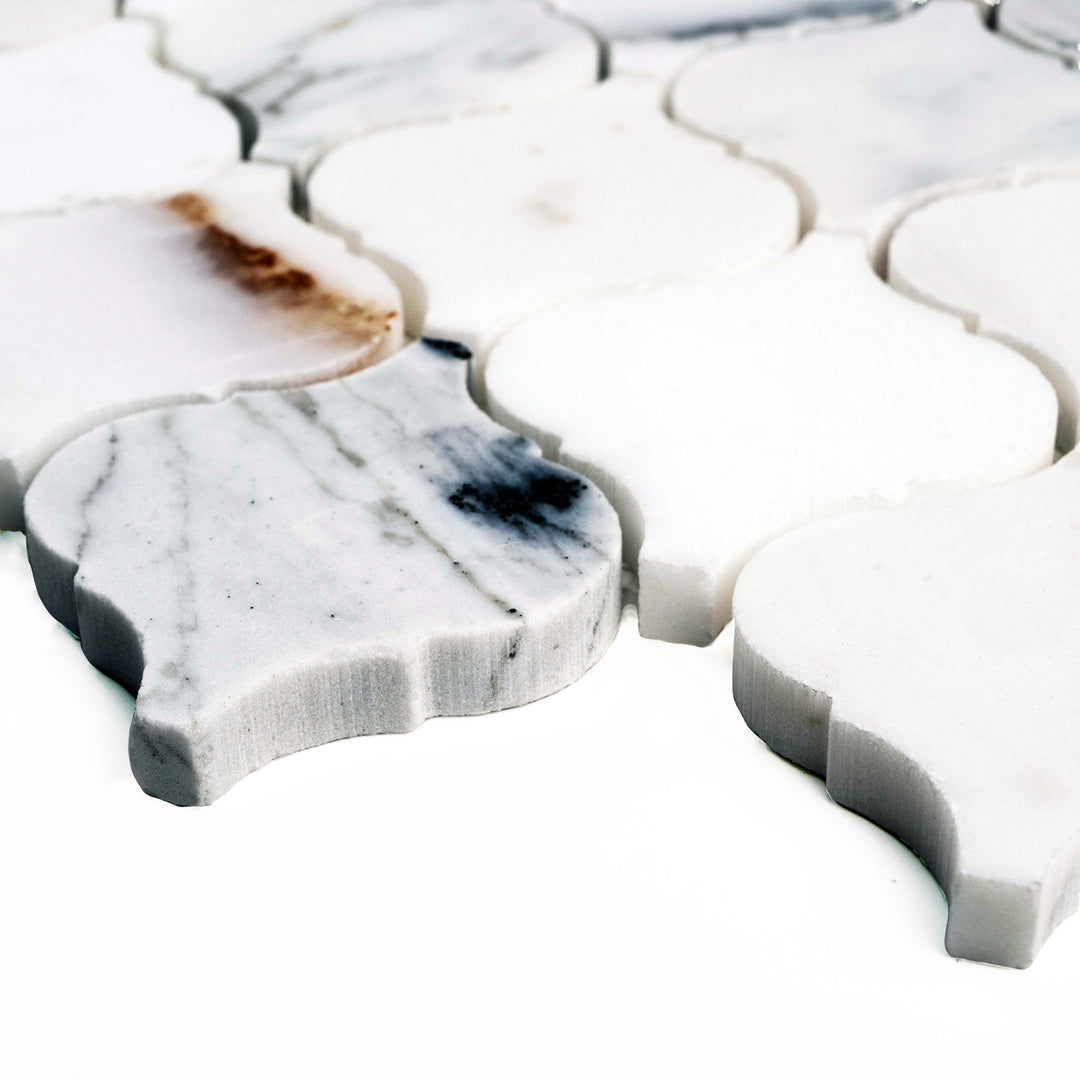 Polished Calacatta Gold 4" Lantern/Arabesque mosaic shown at an angle, highlighting graceful curves and shimmering marble brilliance.