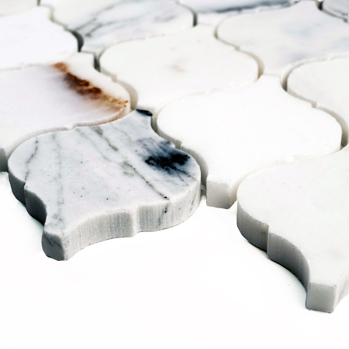 Polished Calacatta Gold 4" Lantern/Arabesque mosaic shown at an angle, highlighting graceful curves and shimmering marble brilliance.