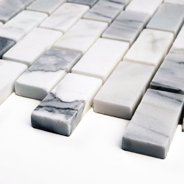 Honed 1x2 Calacatta Gold brick mosaic viewed at an angle, showcasing a sleek subway layout with a smooth matte surface and elegant white marble tones.