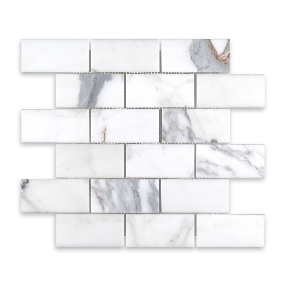 Overhead image of Calacatta Gold Marble 2x4 brick mosaic in a honed finish, showing off a soft matte texture and traditional layout with elegant veining.