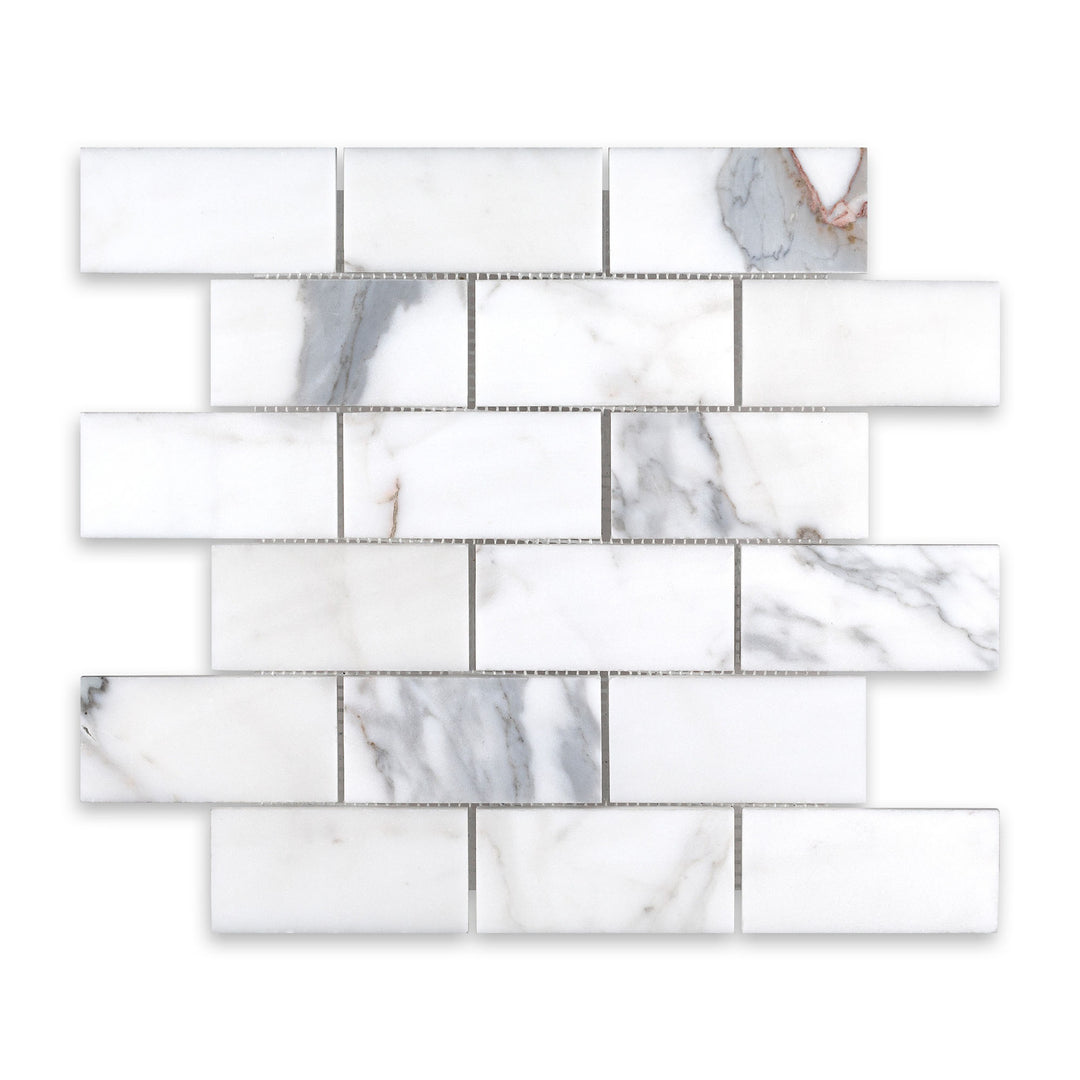 Overhead image of Calacatta Gold Marble 2x4 brick mosaic in a honed finish, showing off a soft matte texture and traditional layout with elegant veining.