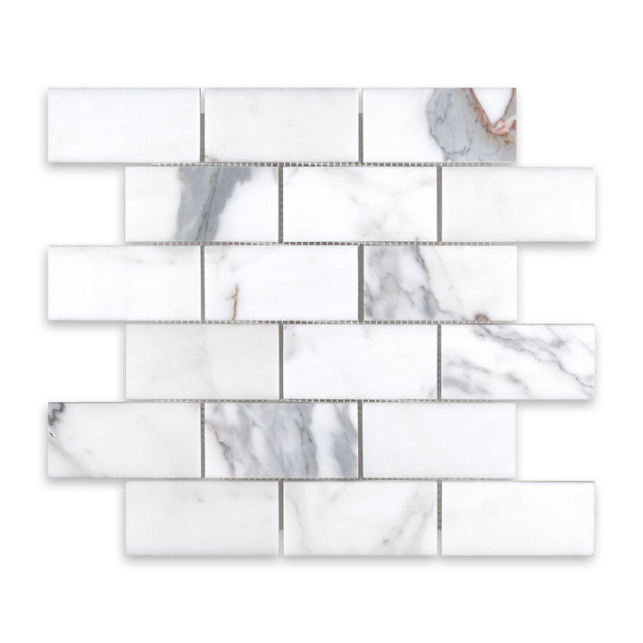 Overhead image of Calacatta Gold Marble 2x4 brick mosaic in a honed finish, showing off a soft matte texture and traditional layout with elegant veining.