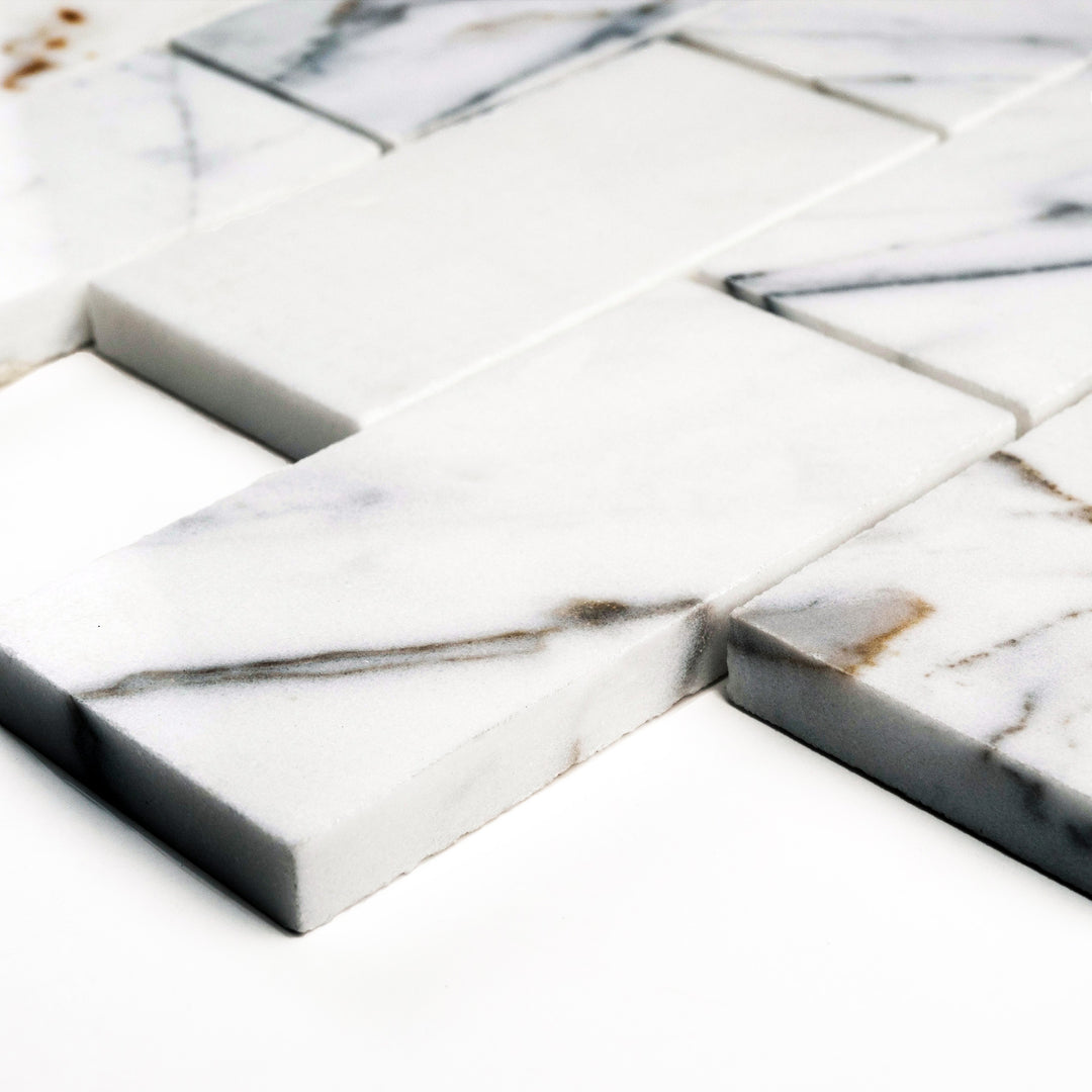Polished Calacatta Gold 2x4 brick mosaic shown from the side, revealing a high-gloss finish that brightens its striking marble pattern.