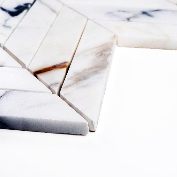 Corner perspective of Calacatta Gold Chevron honed mosaic, displaying a refined V-pattern with muted texture and directional veining.
