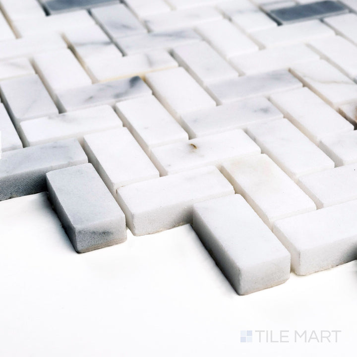 Corner detail of Calacatta Gold Marble 5/8x1-1/4 herringbone polished mosaic highlighting golden veins and sheen.