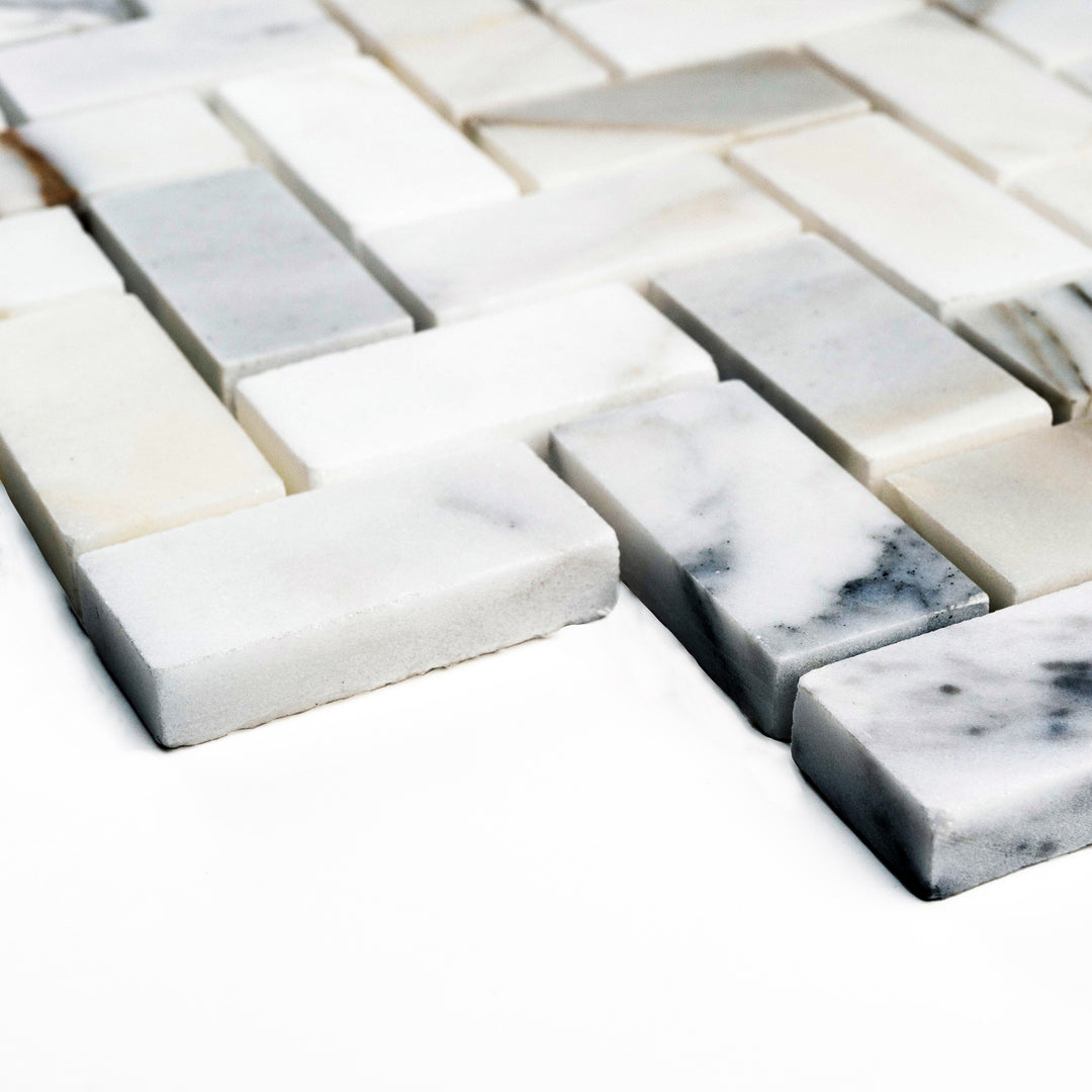 Corner angle of Calacatta Gold 1x2 herringbone honed mosaic, featuring elongated pieces arranged in a classic pattern with soft veining and a smooth finish.