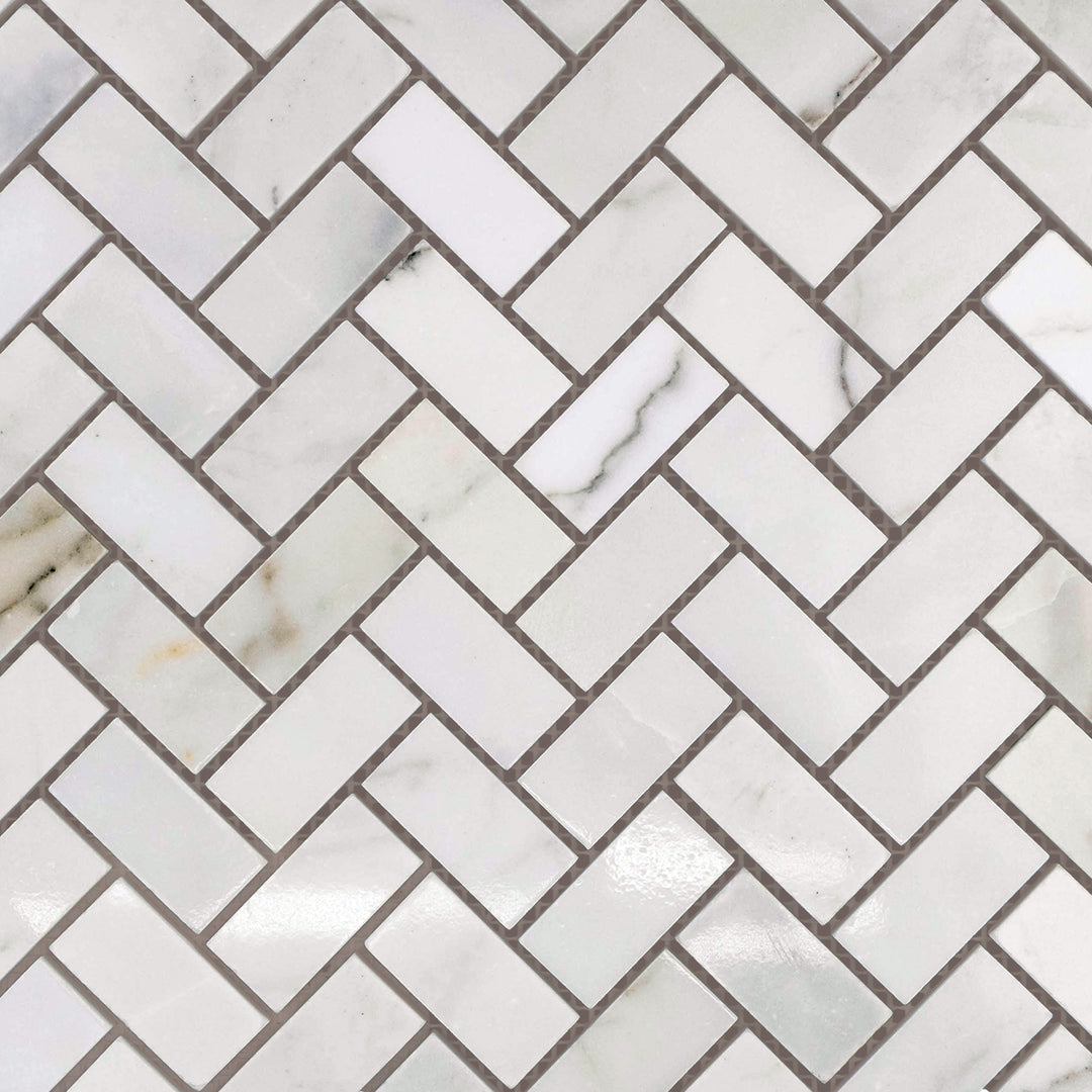 Polished Calacatta Gold Marble 1x2 herringbone mosaic tiles laid out to highlight radiant sheen and intricate layout.