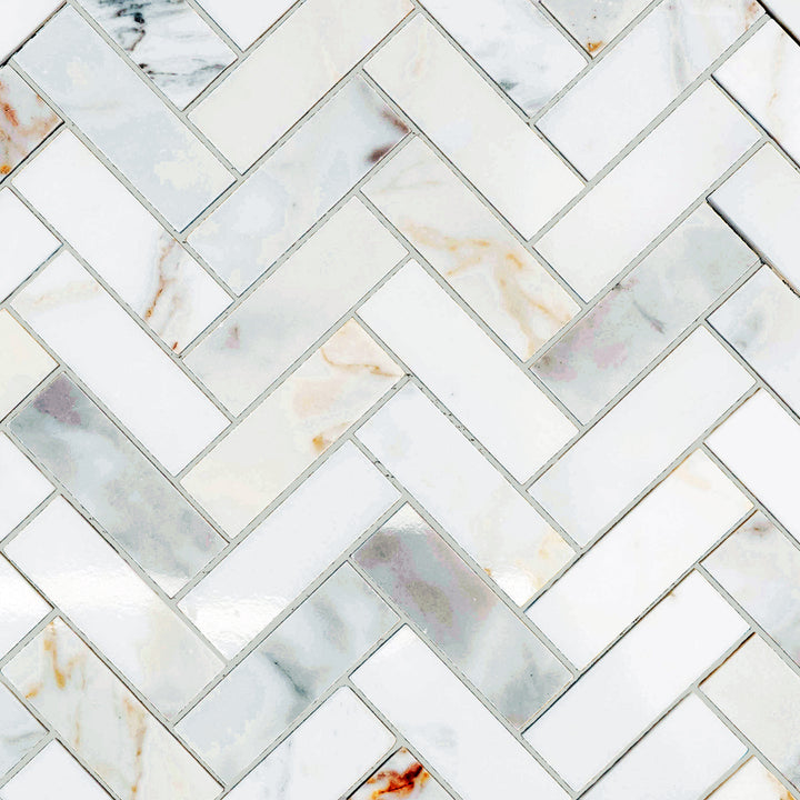 Calacatta Gold Marble 1x3 herringbone polished mosaic presented in an angled layout with glossy texture and elegant curves.