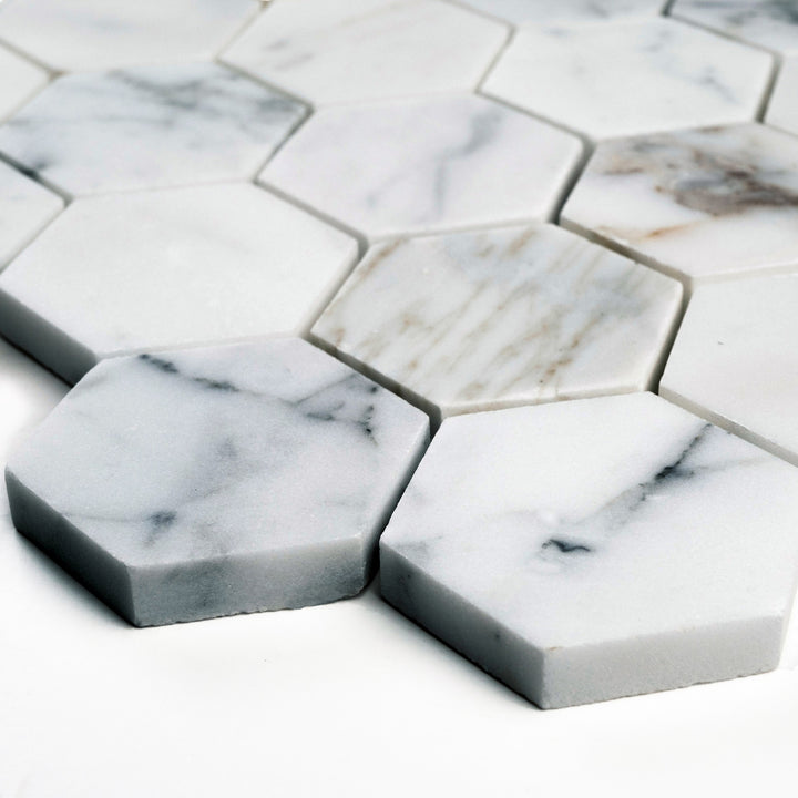 Angled view of Calacatta Gold 2" hexagon honed mosaic, highlighting bold yet refined marble patterning and soft finishes in each hex tile.