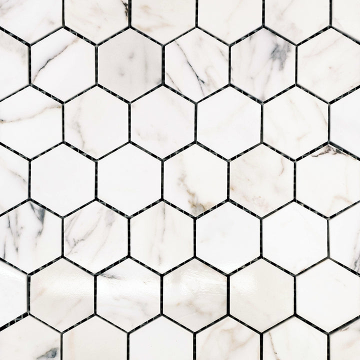 Polished Calacatta Gold Marble 2" hexagon mosaic tiles laid out to showcase a lustrous finish and bold veining.