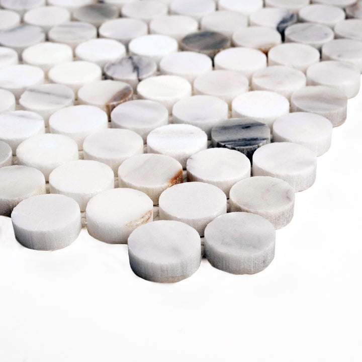 Calacatta Gold penny round mosaic in a honed finish shown at an angle, featuring smooth matte circles and subtle golden veining.