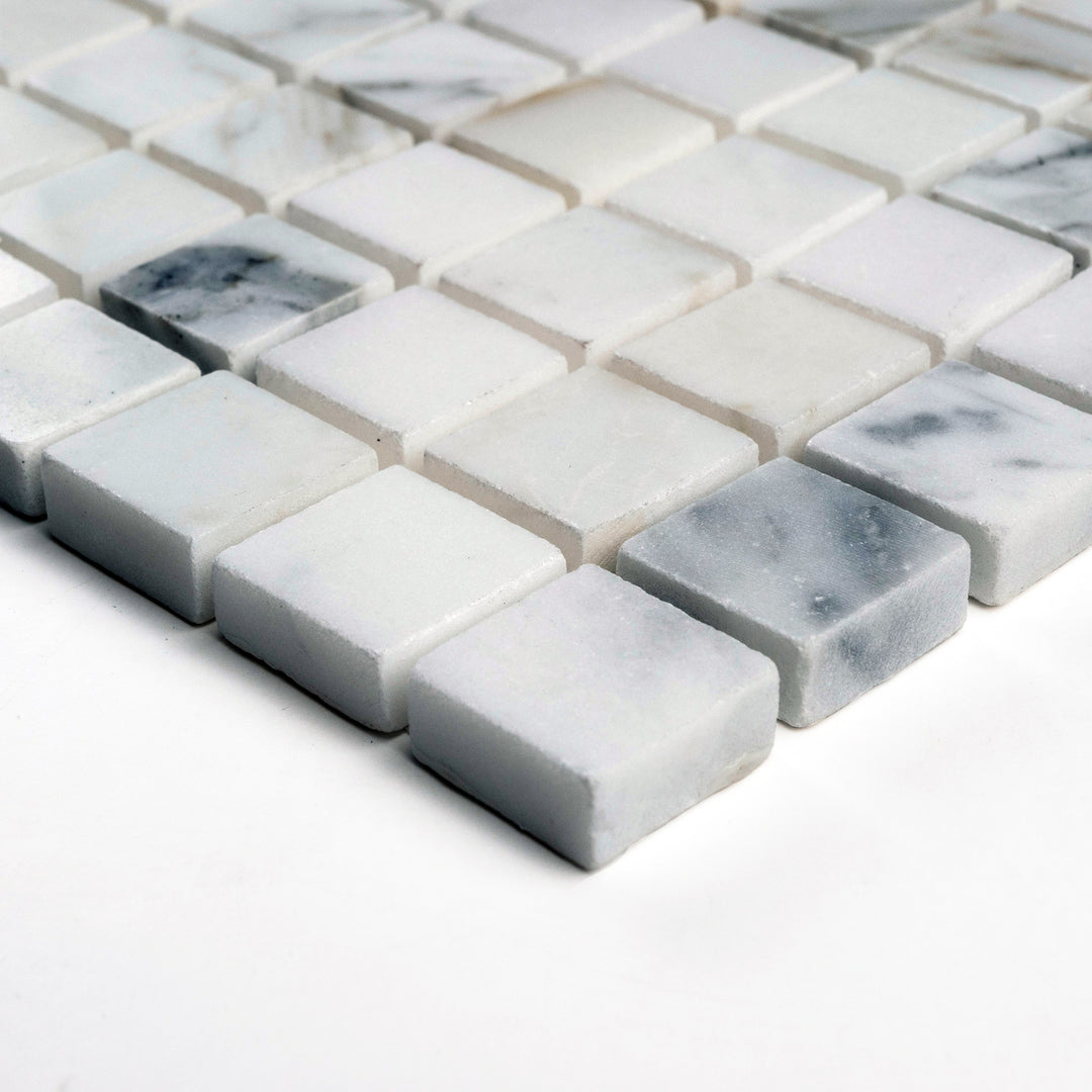 Polished Calacatta Gold 1" square mosaic photographed from the corner, showing luminous tiles and vivid marble veining.