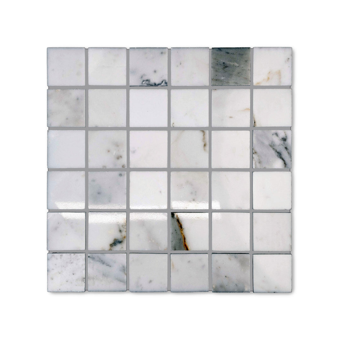 Top-down view of polished 2 inch square Calacatta Gold Marble mosaic, displaying radiant surfaces and bold gold veins across structured tile layout.