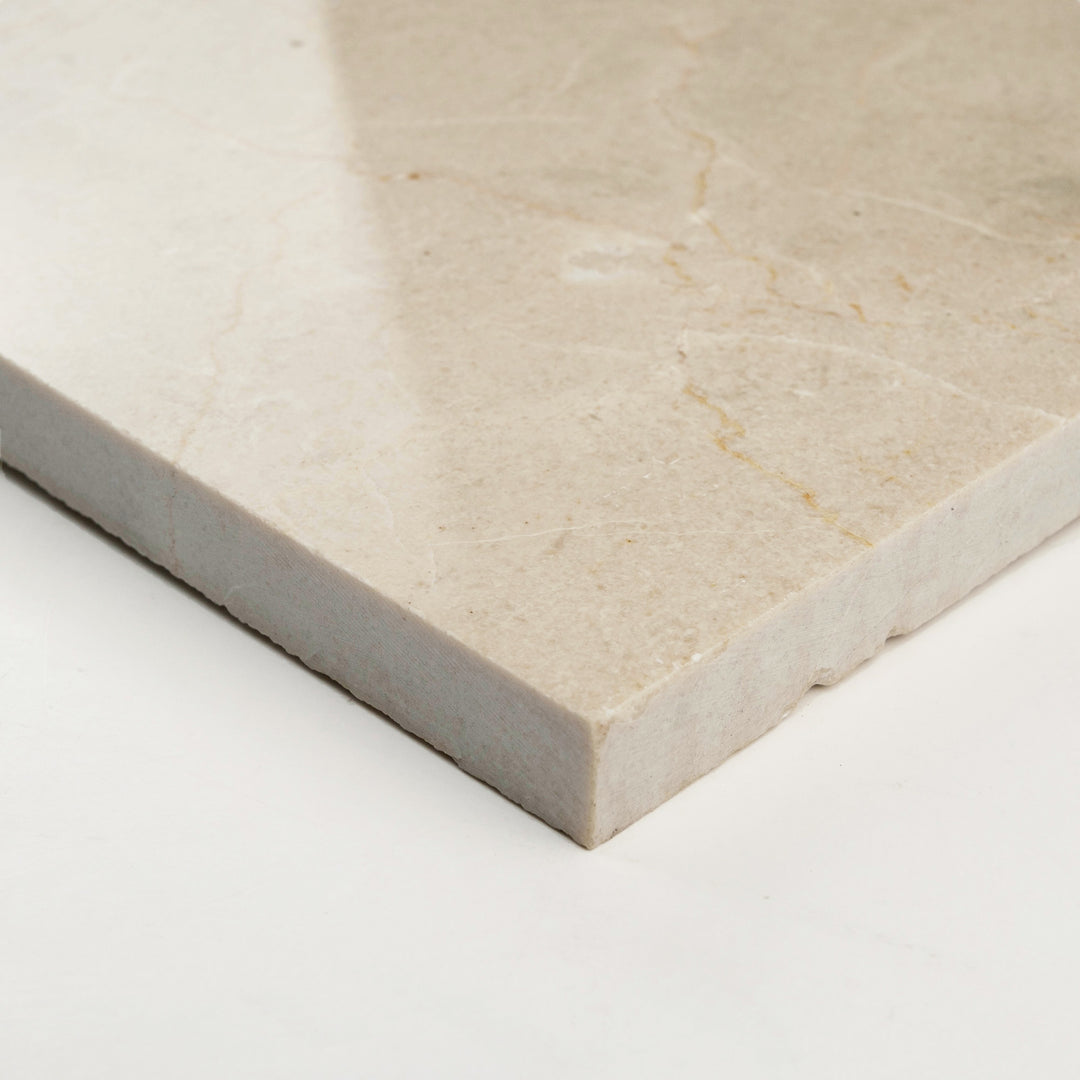 Polished Crema Marfil Classic 3x6 tile, captured at an angle, with a radiant finish that enhances its creamy, neutral hues.