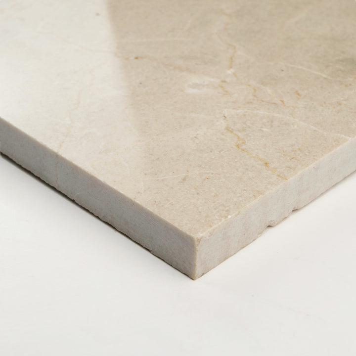Polished 24x24 Crema Marfil Classic tile shown at an angle, with a sleek surface that accentuates its rich, creamy beige appearance.