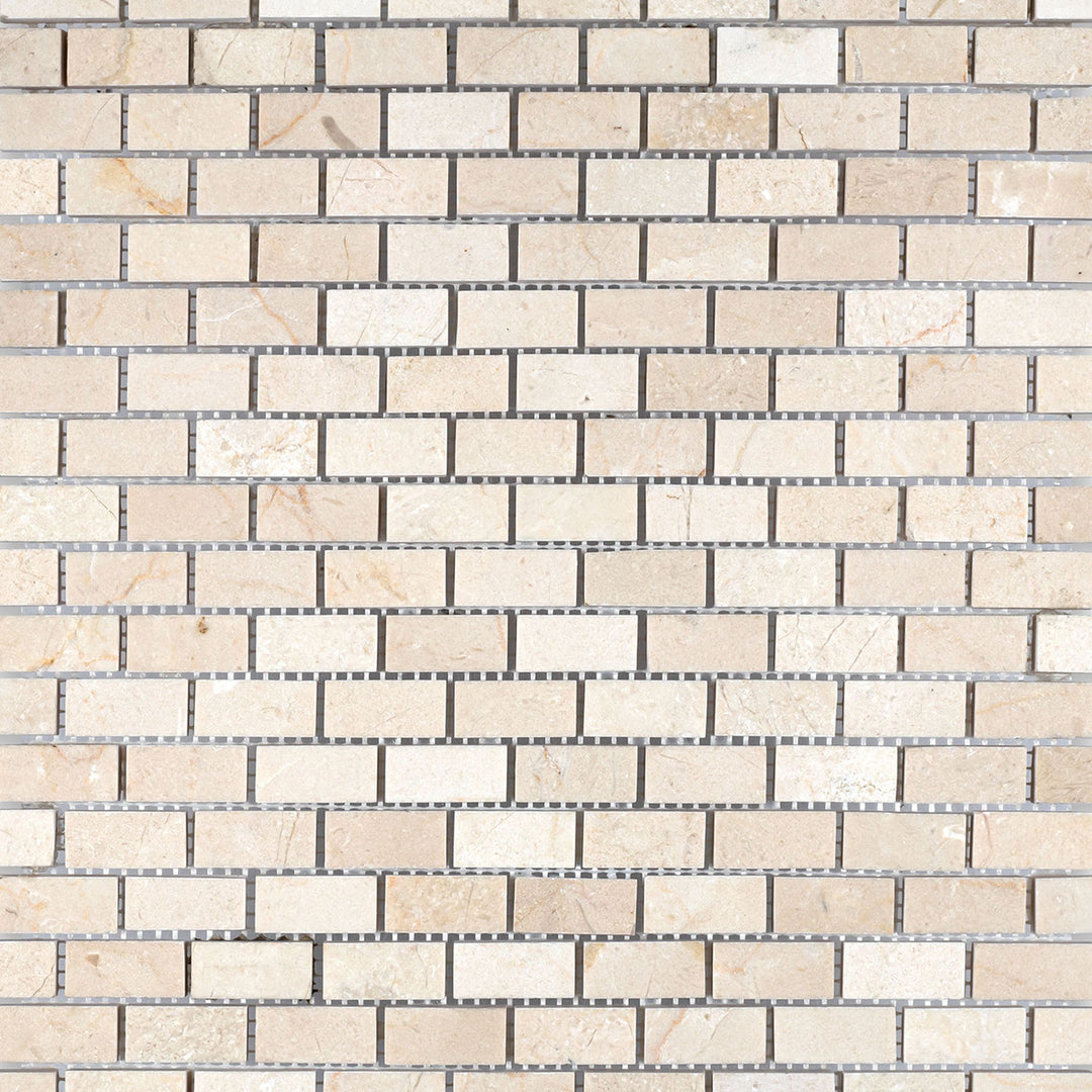 Overview of Crema Marfil Marble 5/8x1-1/4 honed brick mosaic tiles aligned in rows to exhibit uniform matte texture and creamy hue.