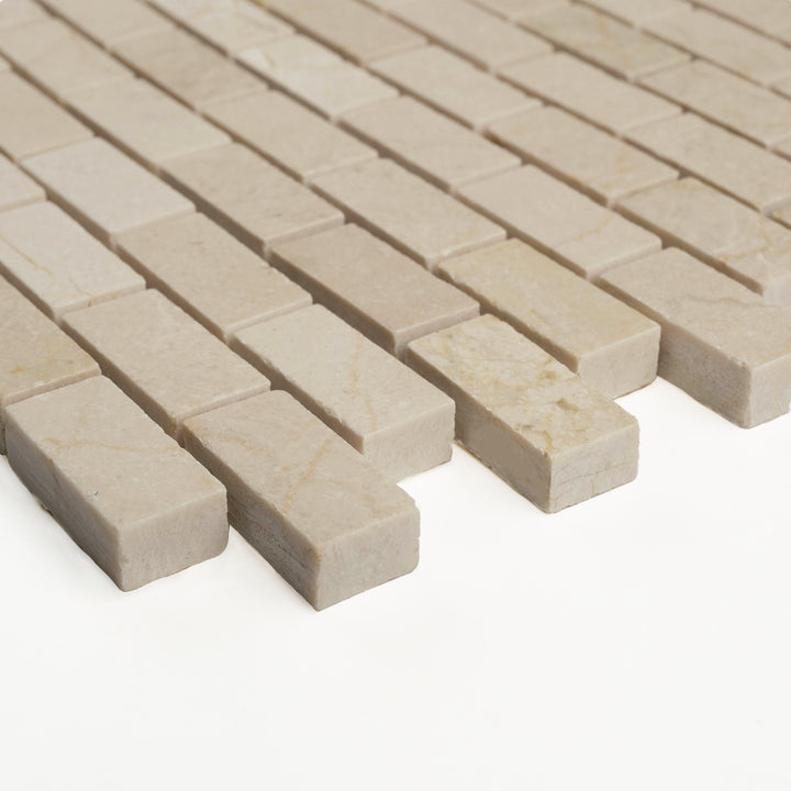 Honed 5/8 by 1 1/4 brick mosaic of Crema Marfil shown from a side perspective, revealing its compact layout and smooth natural texture.