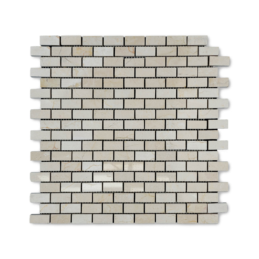 Top-down view of 5/8 by 1-1/4 Crema Marfil Marble brick mosaic in a polished finish, showcasing small rectangular tiles with warm beige tones and reflective surfaces.