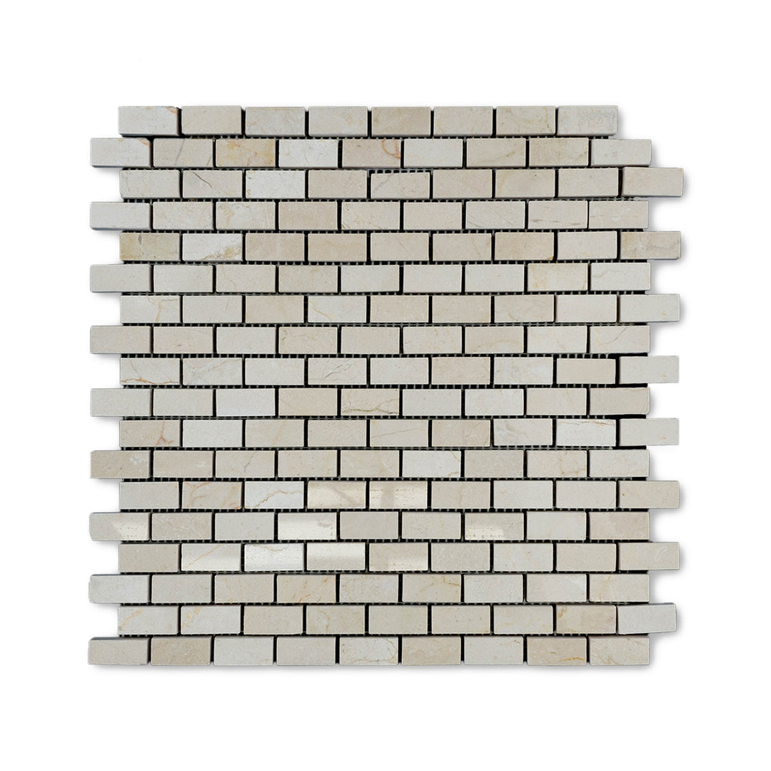 Top-down view of 5/8 by 1-1/4 Crema Marfil Marble brick mosaic in a polished finish, showcasing small rectangular tiles with warm beige tones and reflective surfaces.