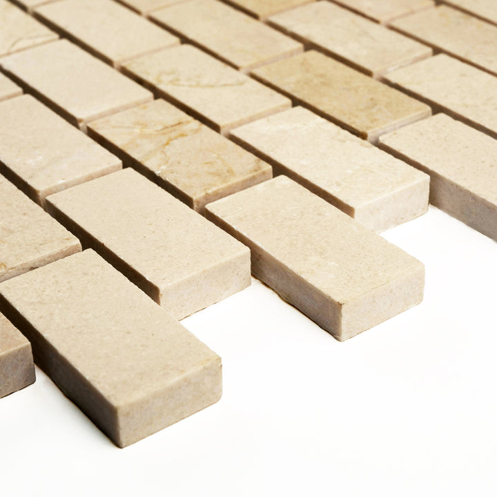 Angle view of honed 1x2 brick Crema Marfil marble mosaic, highlighting the clean linear layout and satin finish.