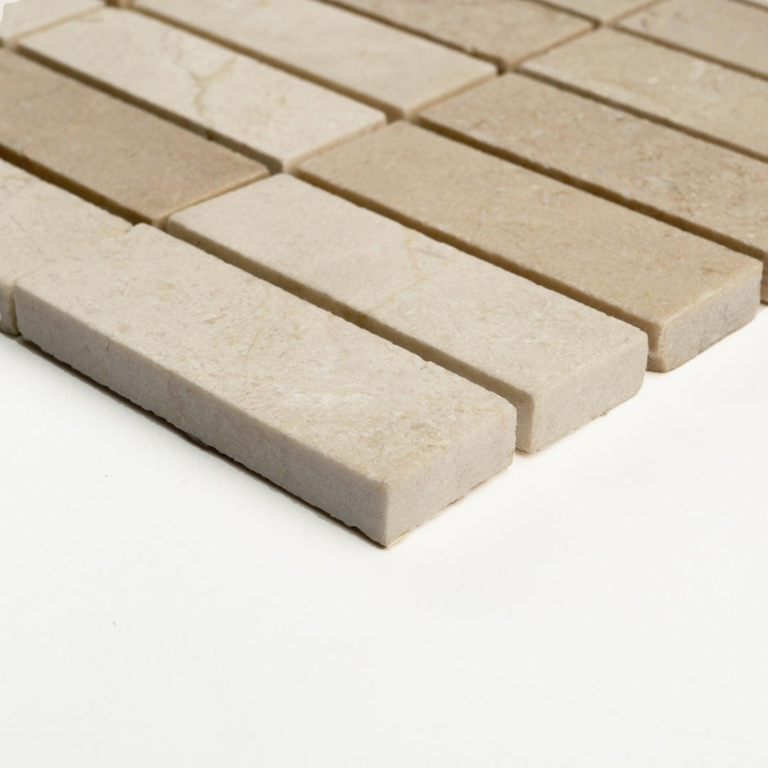 Honed 1x3 stacked mosaic in Crema Marfil marble, photographed from a side view to showcase its elongated format and matte elegance.
