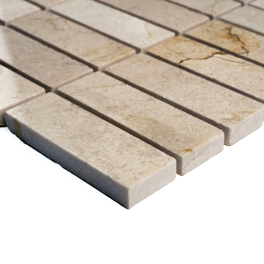 Corner angle of polished 1x3 stacked Crema Marfil mosaic, emphasizing a sleek linear pattern and subtle veining under a glossy finish.