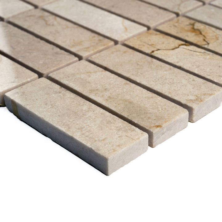 Corner angle of polished 1x3 stacked Crema Marfil mosaic, emphasizing a sleek linear pattern and subtle veining under a glossy finish.
