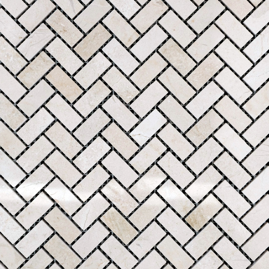 Polished 5/8x1-1/4 herringbone mosaic in Crema Marfil Marble, arranged in a woven overview to highlight its warm beige tones.