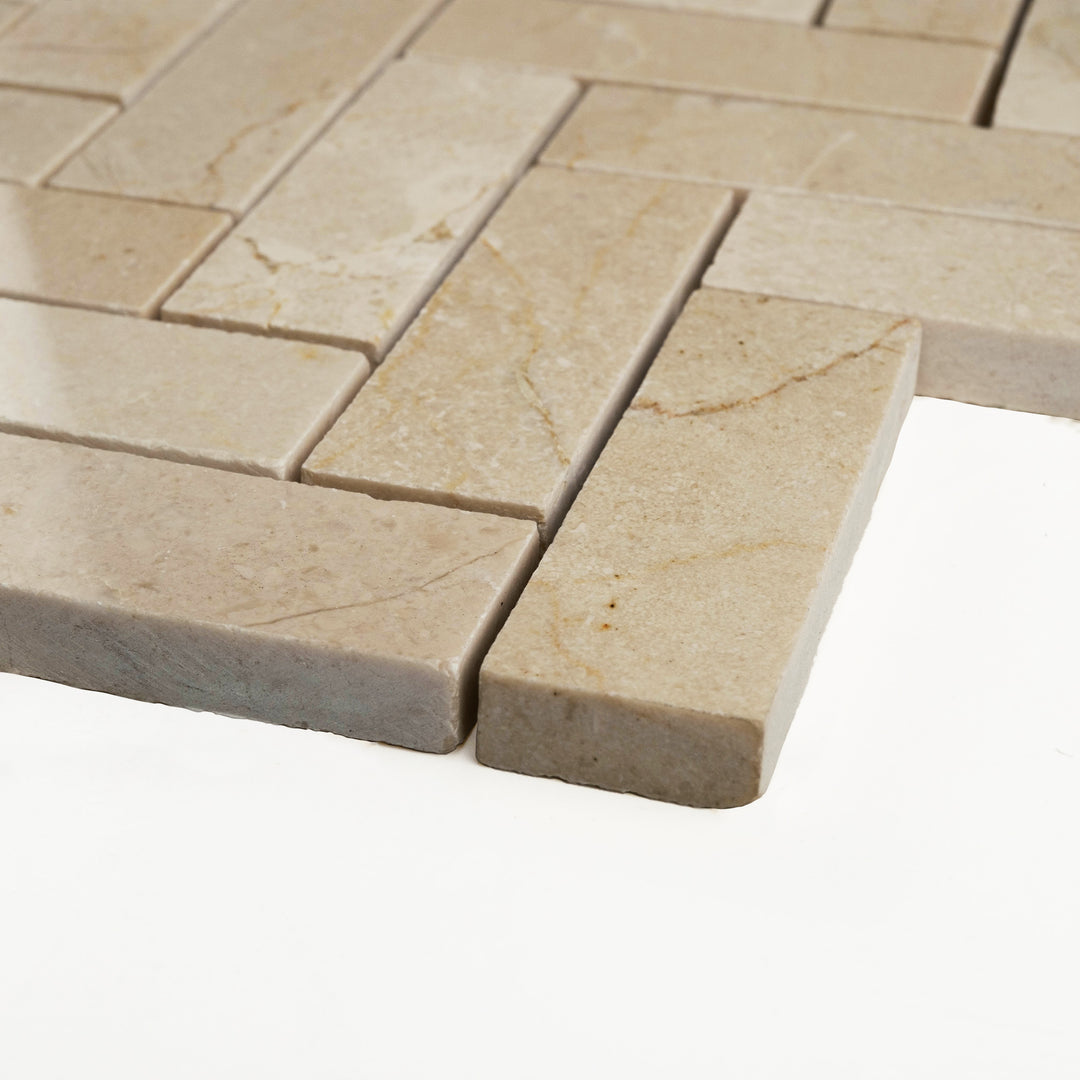 1x3 herringbone Crema Marfil marble mosaic polished to a high gloss, shown from an angled view to accentuate its elongation and elegance.