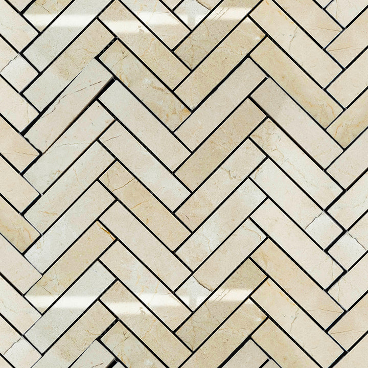 Polished 1x4 herringbone mosaic tile layout of Crema Marfil Marble shown in a clean, diagonal arrangement.