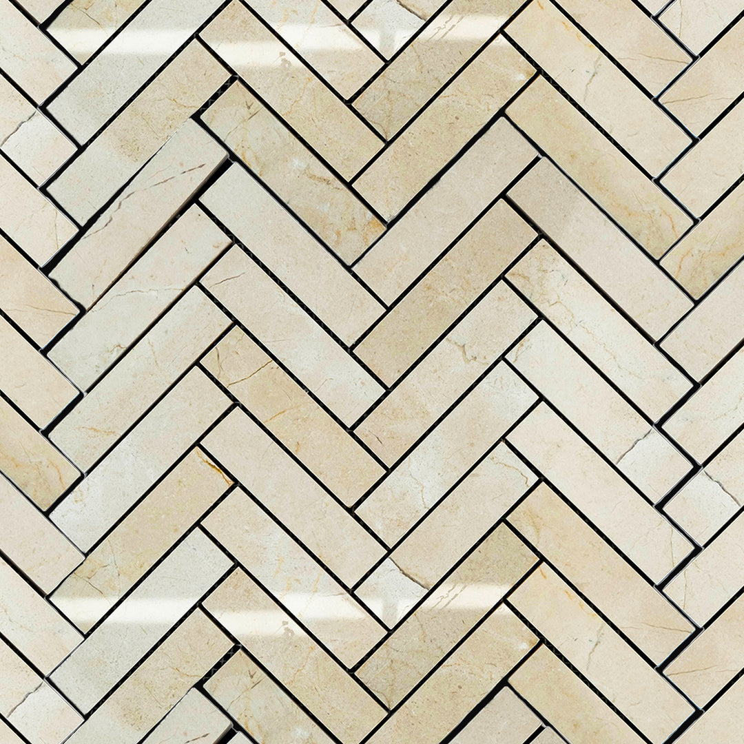 Polished 1x4 herringbone mosaic tile layout of Crema Marfil Marble shown in a clean, diagonal arrangement.