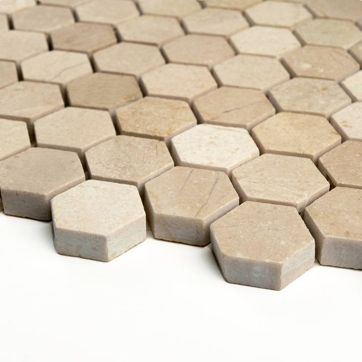 Honed 1 inch hexagon Crema Marfil marble mosaic captured from a corner angle, highlighting the clean honeycomb layout and warm matte tones.