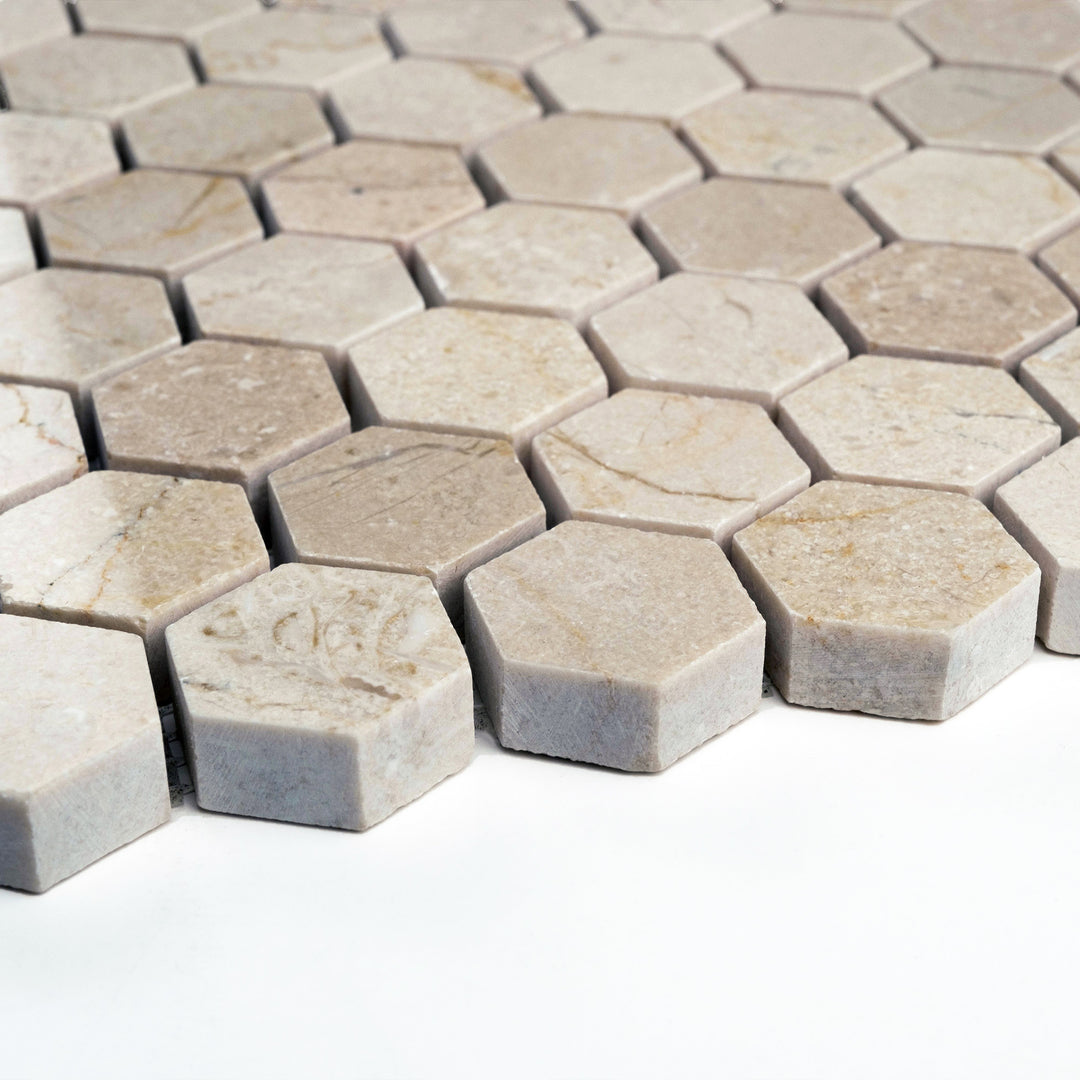 Polished 1 inch hexagon Crema Marfil mosaic seen from the side, featuring geometric precision and a glossy, light-catching finish.