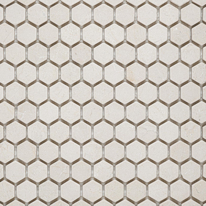 Crema Marfil Marble 1" hexagon tumbled mosaic overview showing rounded edges and aged stone texture.
