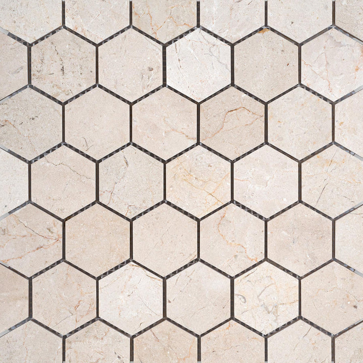 Overview shot of 2" hexagon honed mosaic made with Crema Marfil Marble, displaying a balanced neutral tone.