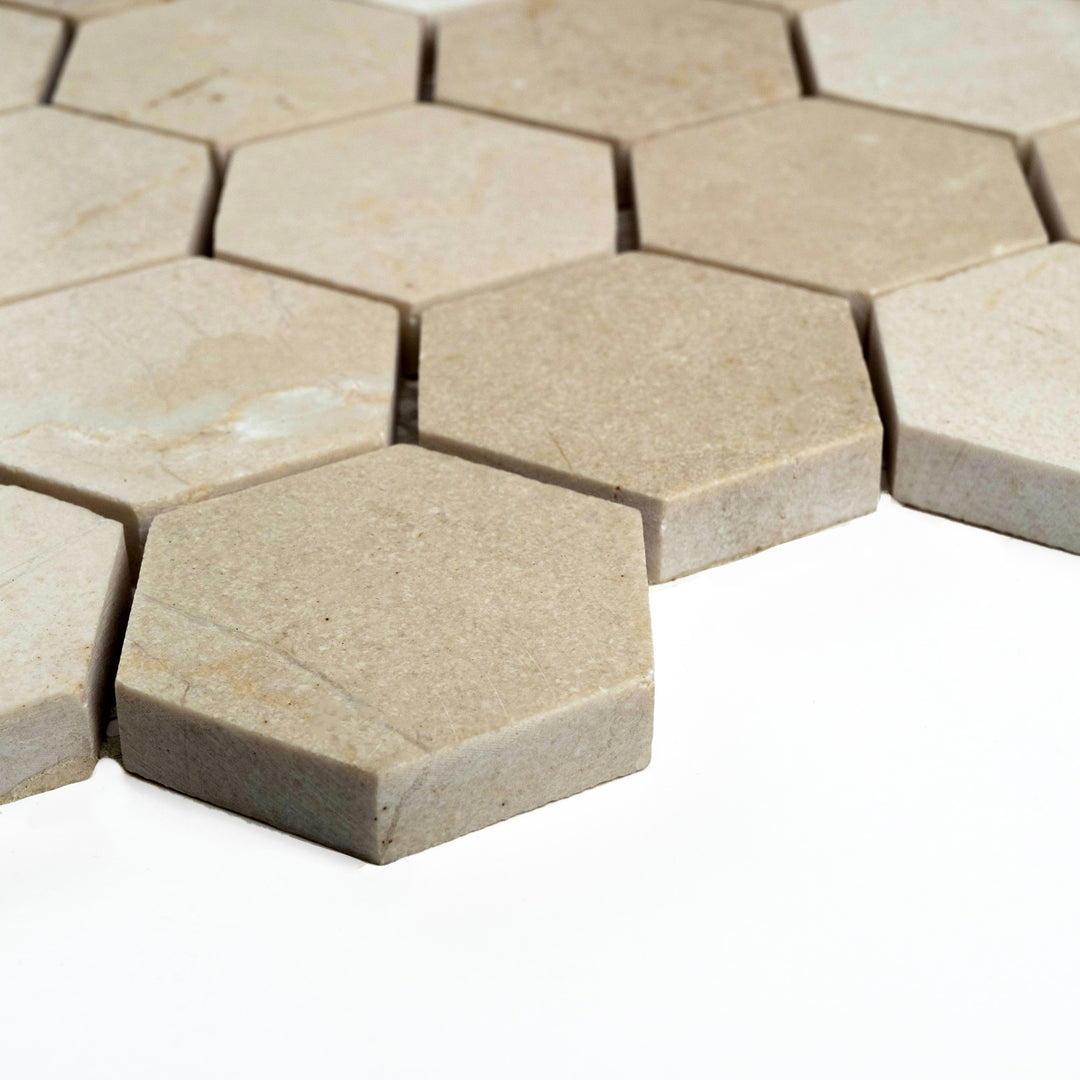 2 inch hexagon mosaic in honed Crema Marfil marble shown at a corner angle, revealing a smooth honeycomb layout with a soft matte finish.