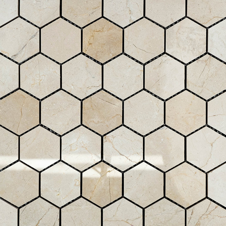 Crema Marfil Marble 2" polished hexagon mosaic tiles laid out to showcase their reflective finish and warm beige hue.