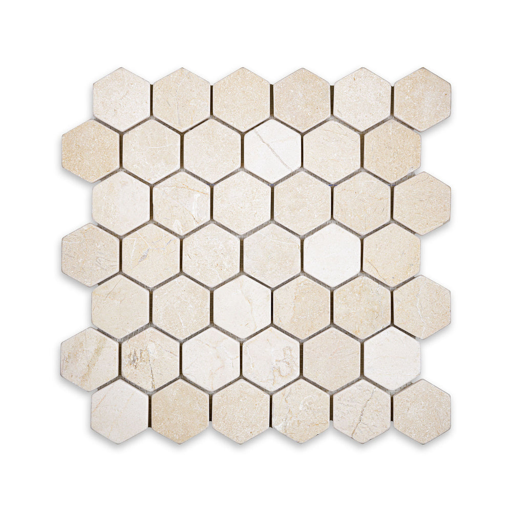 Overhead view of tumbled 2 inch hexagon mosaic in Crema Marfil Marble, combining a worn texture with soft veining and natural stone character.