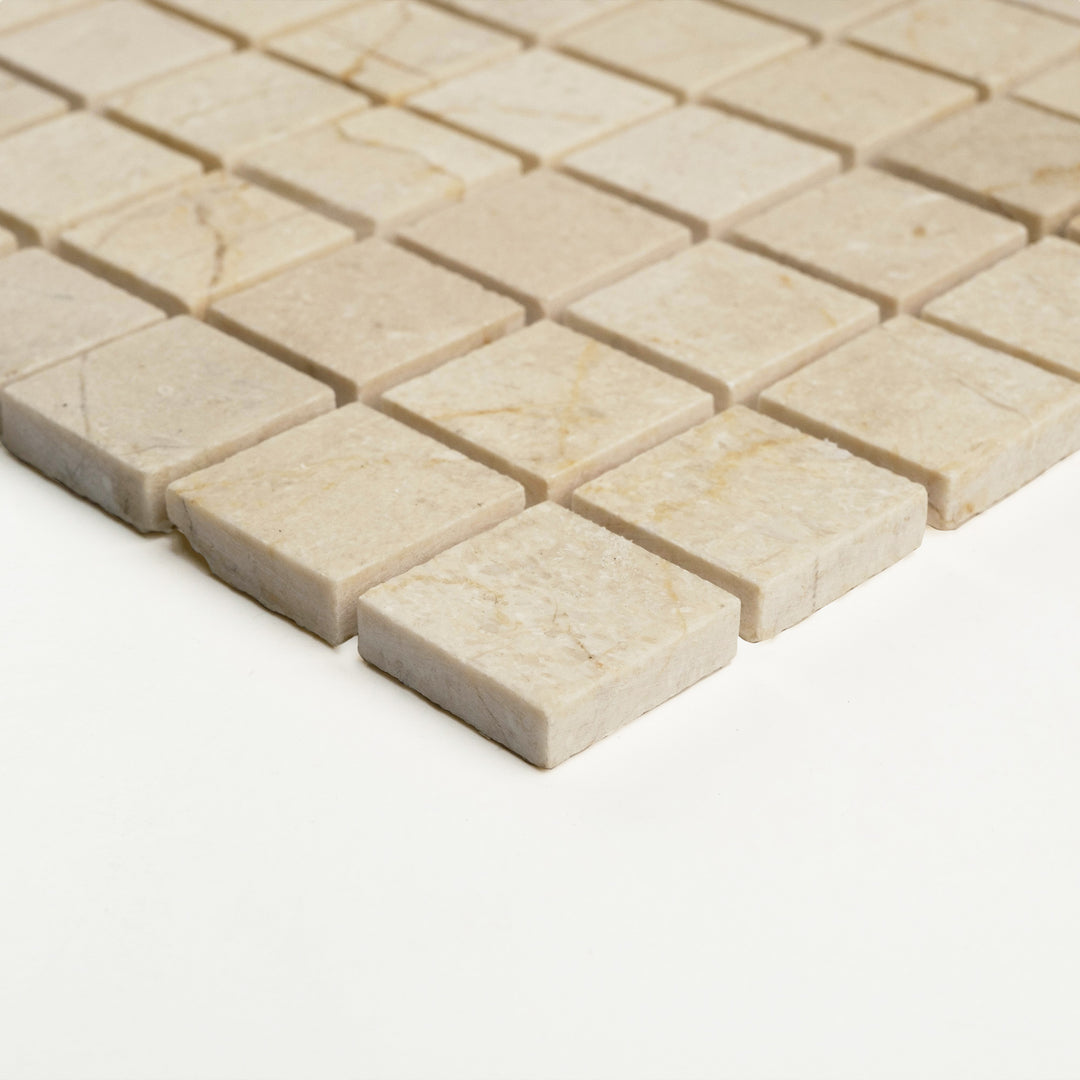 Corner view of 1 inch square Crema Marfil marble mosaic in a honed finish, showing its clean edges and velvety stone texture.