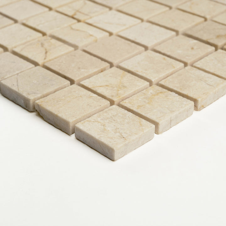 Corner view of 1 inch square Crema Marfil marble mosaic in a honed finish, showing its clean edges and velvety stone texture.