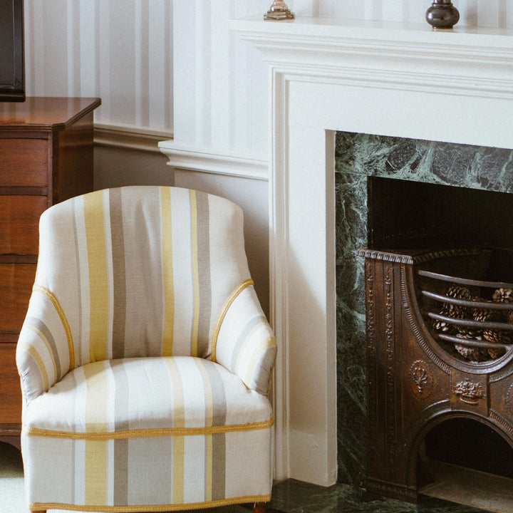Striped armchair in a room with a green tiled fireplace