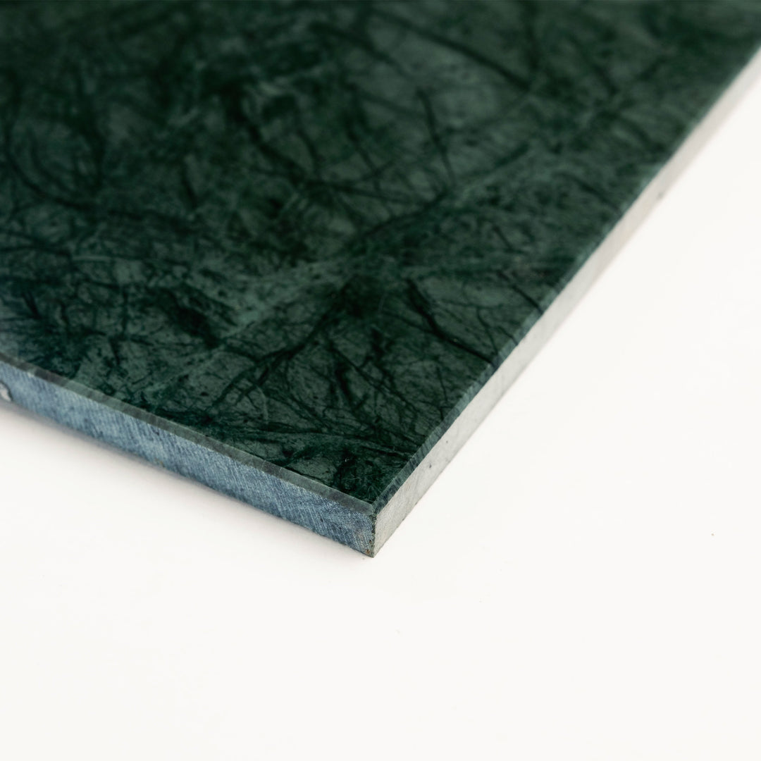 Polished 12x24 Empress Green marble tile displayed at a side angle, revealing its elongated form and rich emerald tones with a reflective surface.