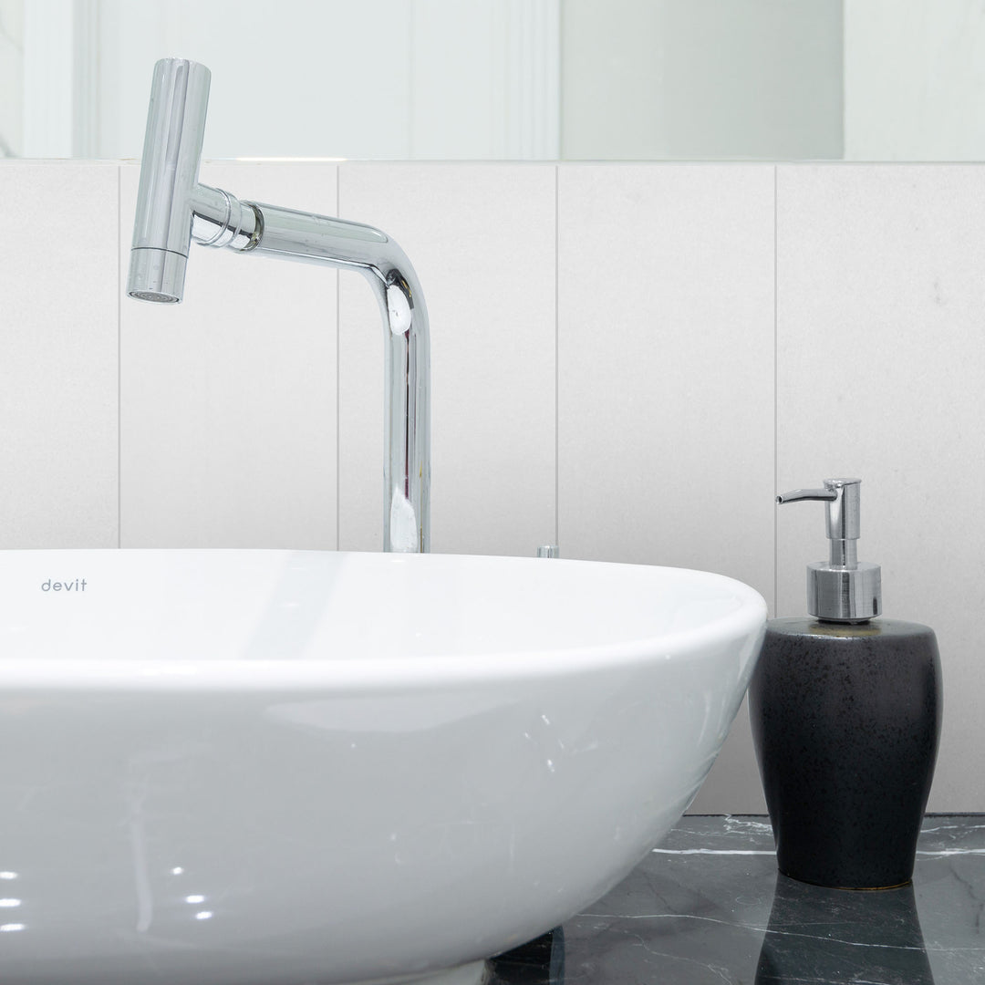 Modern bathroom setup with a white sink, chrome faucet, and black soap dispenser against a tiled wall.