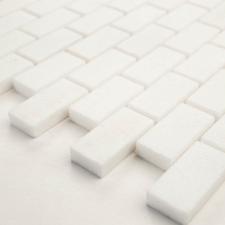 1x2 brick mosaic in honed Thassos White marble, shown at a diagonal angle to bring out its clean grid layout and soft honed surface.