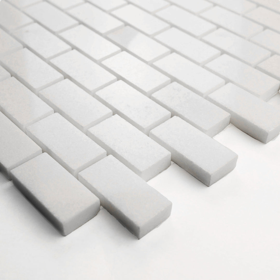 Polished 1x2 brick mosaic in Thassos White marble, corner-shot presentation reveals its elegant shine and precise layout.