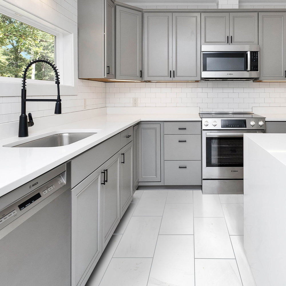 Modern kitchen with gray cabinets, stainless steel appliances, and white countertops.